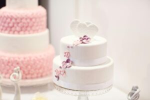 Home A beautifully decorated white wedding cake with elegant floral designs, perfect for weddings.
